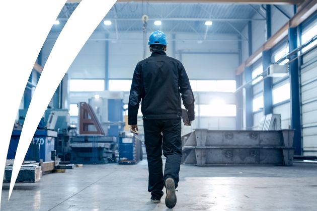 Skilled worker wearing a hard hat during an inspection in an industrial hall.